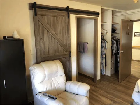Room with a white reclining chair, barn-style sliding door and open wardrobe