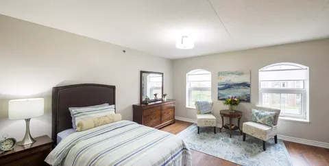 Bedroom with a single bed, two armchairs and windows
