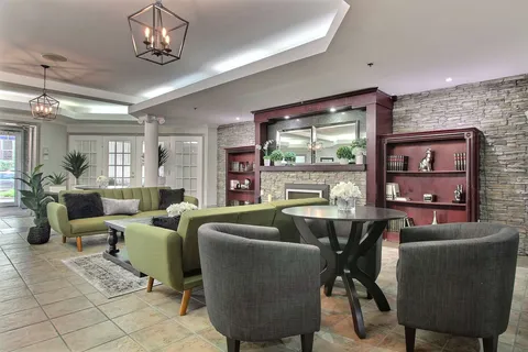Lounge with armchairs, tables and a stone fireplace.