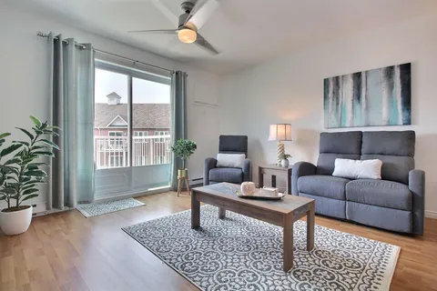 Suite living room with grey armchairs and a patio door.