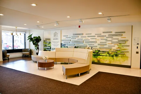 Curved seating and a round table beside windows and a landscape donor wall