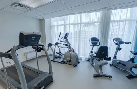 Fitness room with a treadmill, exercise bikes and large windows