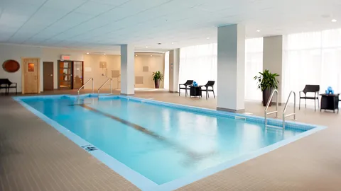 Indoor swimming pool with tiled deck, handrails and tall windows