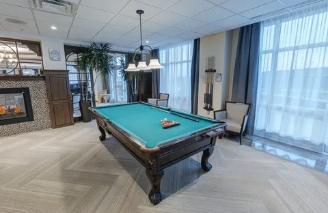 Green billiard table beside curtained windows and a fireplace