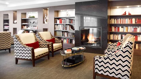 Patterned armchairs beside a fireplace and bookshelves