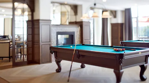 Billiard table with balls and cues beside a fireplace