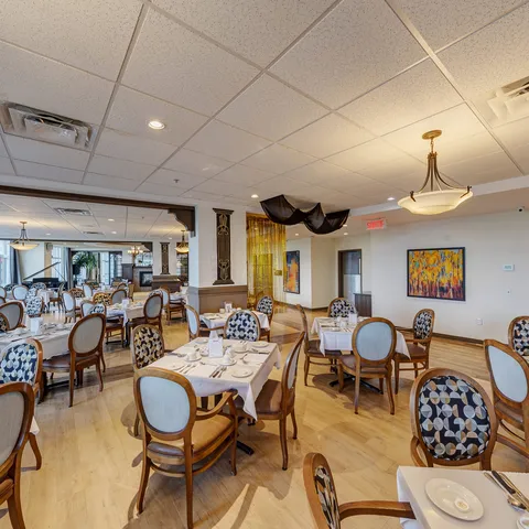 Dining tables and upholstered chairs beside colourful paintings