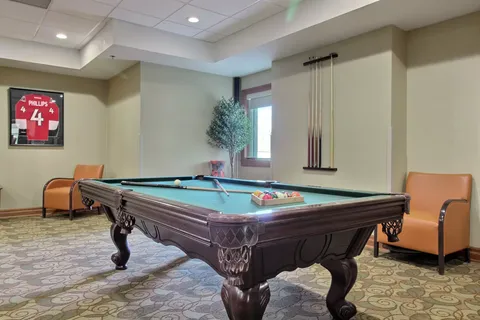 Billiards table beside chairs and a framed hockey jersey