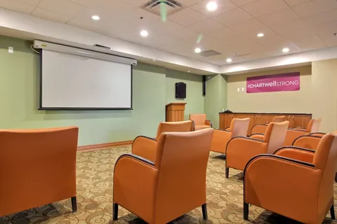 Room with orange armchairs facing a blank projection screen