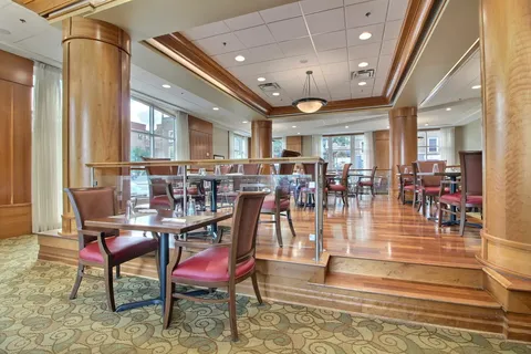 Dining room with wooden columns, tables and red upholstered chairs