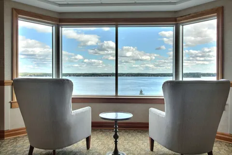 Two armchairs beside large windows overlooking the water