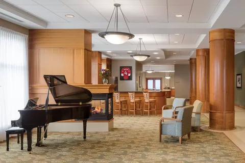 Grand piano beside upholstered chairs and a wooden counter