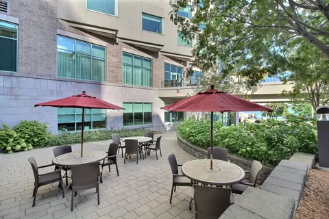 Patio with round tables and red umbrellas beside the residence building