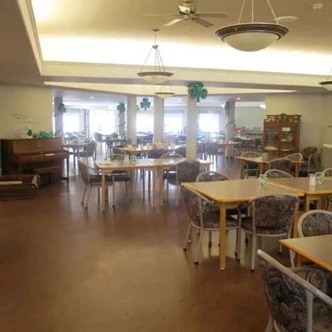 Dining room with wooden tables, patterned chairs and a piano.