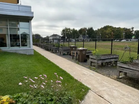 Garden path beside lawn, raised planters and a glass-walled room
