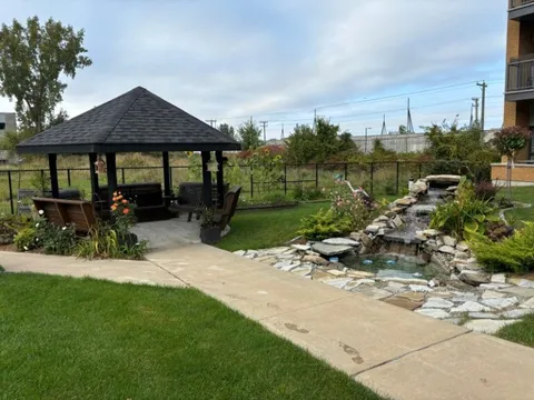 Garden with a gazebo, benches, flowers and a stone water feature