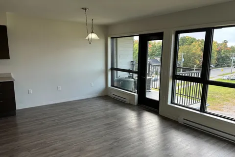 Empty room with wood-look flooring, large windows and a glass balcony door