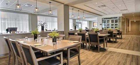 Dining room with set tables, upholstered chairs and pendant lights.