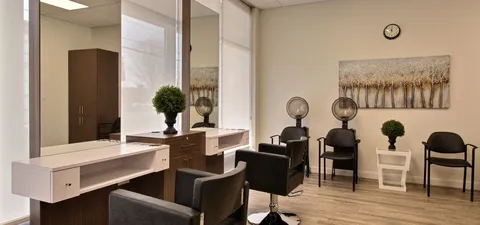 Salon with styling chairs, mirrors and hair dryers.