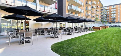 Patio with tables, chairs and umbrellas beside the building.