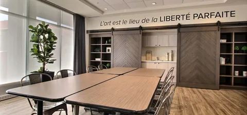 Activity room with long wooden tables and storage cabinets.