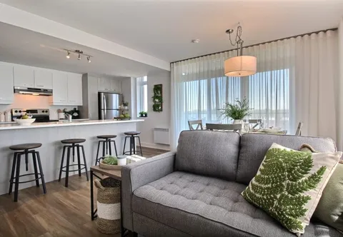 Living room with a sofa beside an open kitchen and dining table.