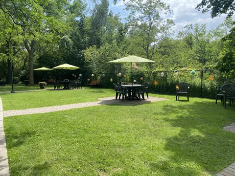 Garden with lawn, paved paths, patio tables and green umbrellas