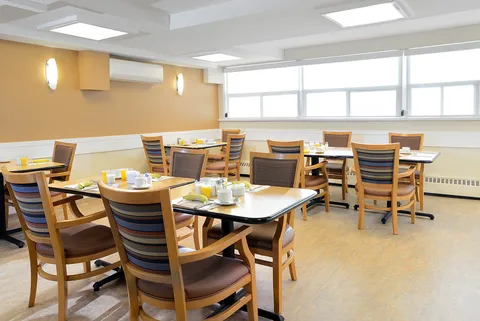 Dining area with wooden tables and chairs beside large windows
