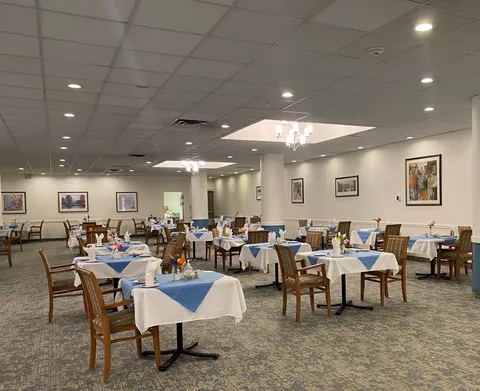 Dining room with white and blue tablecloths, wooden chairs and framed artwork