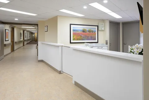 White reception counter beside a corridor and framed landscape artwork