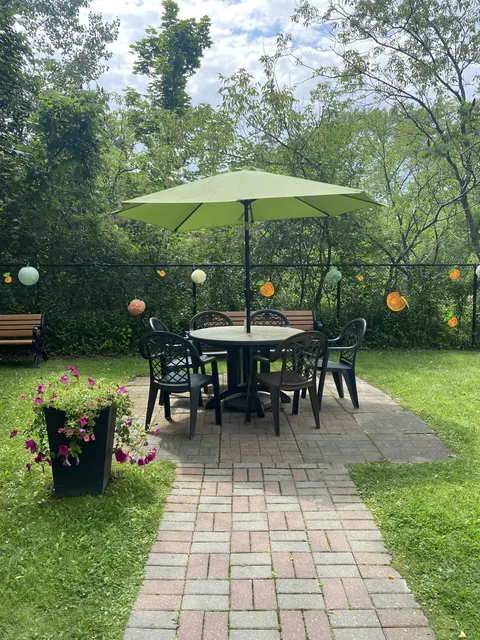 Paved garden path leading to a patio table beneath a green umbrella