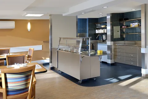 Dining area with a stainless steel serving counter and wooden chairs