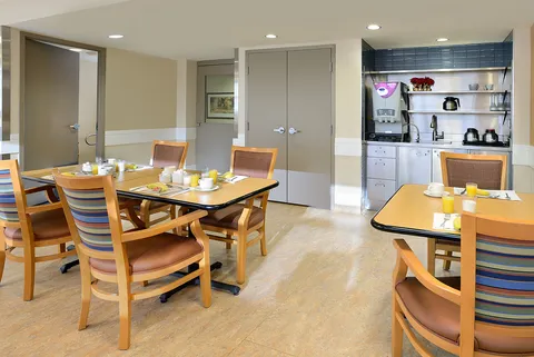 Dining tables with wooden chairs, cups and a serving counter