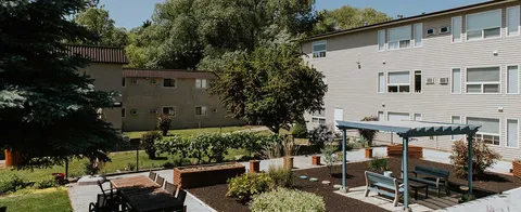 Residence buildings surrounding a landscaped courtyard with benches and a pergola