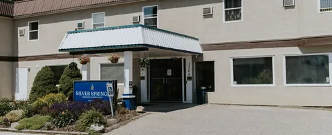 Covered residence entrance beside a driveway and flower beds