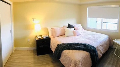 Bedroom with a double bed, bedside table and large window.