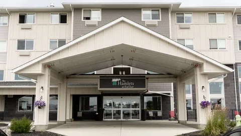 Covered main entrance with glass doors and surrounding flower beds.