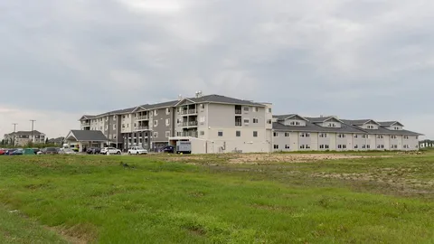 Residence buildings beside a lawn under an overcast sky.