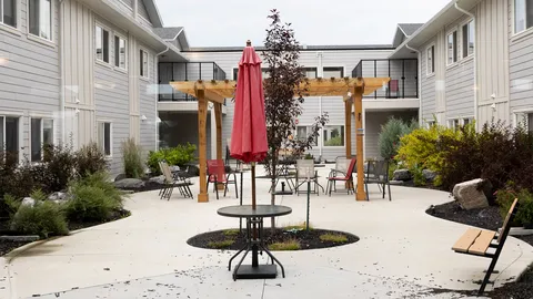 Courtyard with seating, umbrellas, planting beds and a pergola.