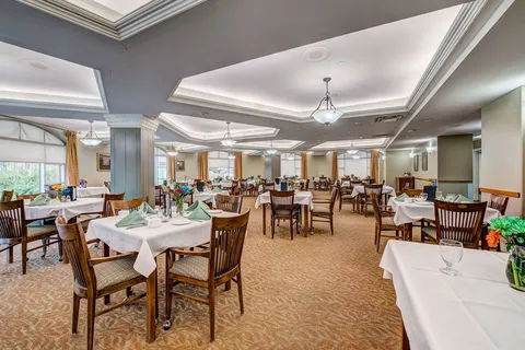 Dining room with set tables, wooden chairs and windows.