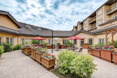 Residence building around a courtyard with raised planters and patio tables.