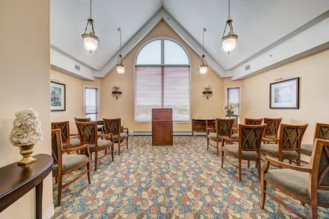 Chapel with rows of wooden chairs and an arched window.