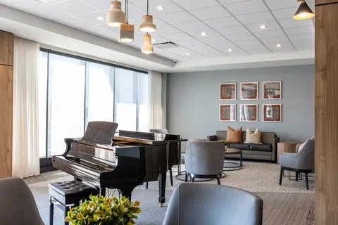 Room with a grand piano, armchairs and a sofa beside large windows