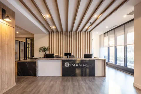 Reception desk beneath wooden ceiling slats beside large windows