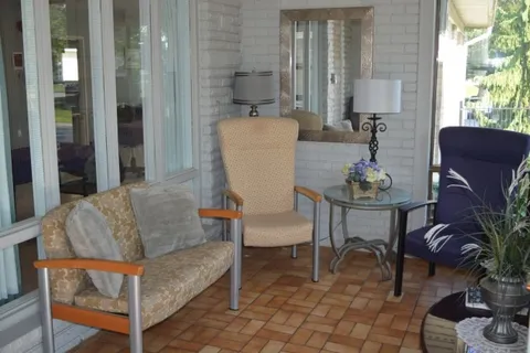 Covered patio with upholstered chairs and brick paving