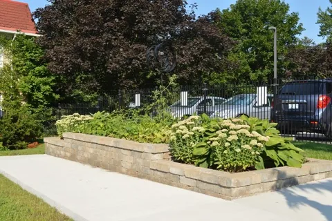 Raised garden bed beside a path and black metal fence