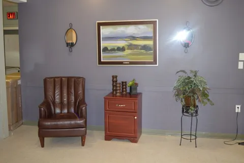 Brown leather armchair beside a wooden cabinet and a landscape painting