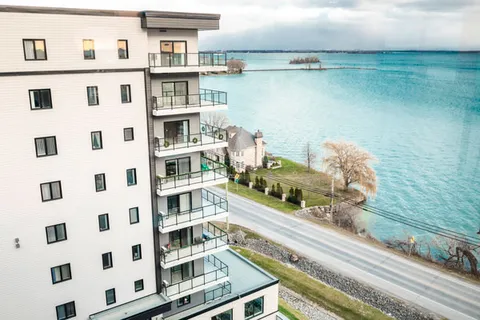 Residence building with balconies beside a road and a broad body of water