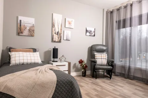 Bedroom with a single bed, bedside table, recliner and framed landscape pictures