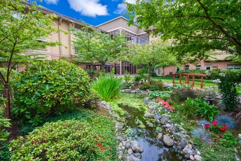 Garden pond, shrubs and a red footbridge beside the residence